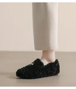 Close-up of black fuzzy faux fur loafers with silver accents on a model for autumn style