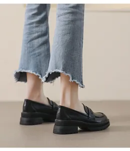 Vista lateral de mocasines negros con plataforma usados con vaqueros de campana azules