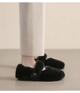 Dettaglio delle ballerine in peluche nero con morbida ecopelliccia e bottone decorativo