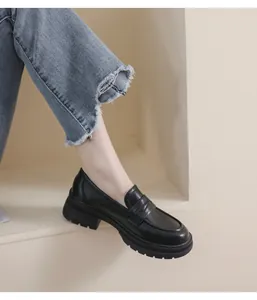 Detalle de mocasines negros con plataforma y suela dentada usados con vaqueros deshilachados
