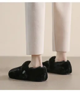 Dettaglio delle scarpe basse in pelliccia sintetica nera indossate da una modella