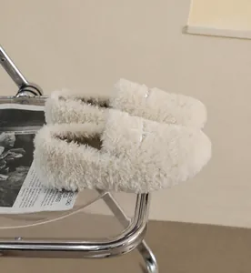 Detail of plush cream faux fur flats with cross-stitch design on a designer chair