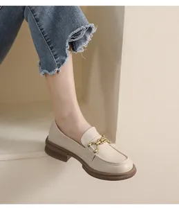 Détail de mocassins crème avec boucle dorée et semelle plateforme marron épaisse