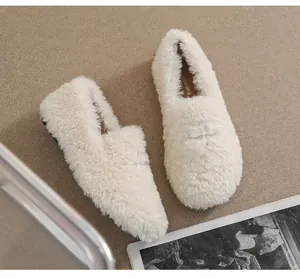 Detailed view of plush beige loafers featuring soft faux fur and silver metal buckle