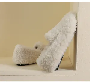 Close-up of plush off-white faux fur loafers with soft texture and black durable soles