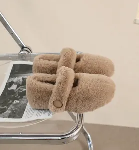 Dettaglio delle mule in pelliccia sintetica color cammello con cinturino a fibbia su sedia