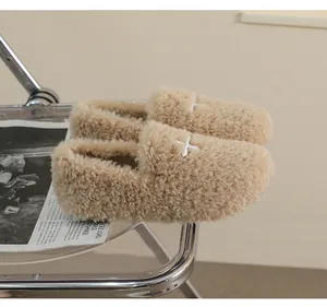Detailed view of beige plush loafers with white cross-stitch detail on acrylic chair