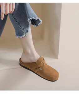Dettaglio di sabot stile Birkenstock in camoscio marrone con cinturino regolabile