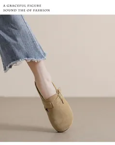 Dettaglio degli zoccoli in camoscio cammello con fibbia e jeans con bordo a frange