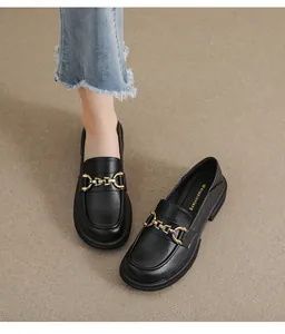 Vue de dessus de mocassins en cuir noir mat avec chaîne dorée et jean décontracté
