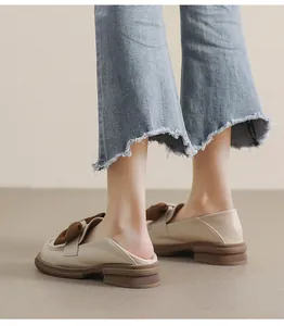 Vista lateral de mocasines de plataforma crema con lazo marrón y vaqueros azules