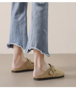 Dettaglio sabot in camoscio kaki con fibbia in bronzo e jeans con orlo vivo