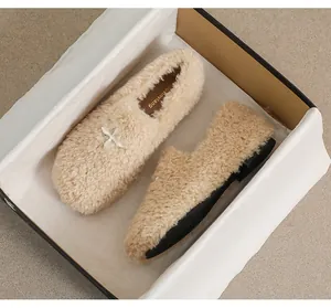 Detail of beige faux fur flats with white satin bow inside a premium gift box