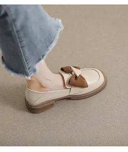 Detalle de mocasines beige con lazo marrón y suela gruesa antideslizante puestos en modelo
