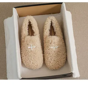 Detail view of beige fuzzy loafer flats with plush texture and star ornament in a gift box
