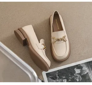 Détail de mocassins beige avec boucle mors dorée et talons épais marrons en vue de dessus