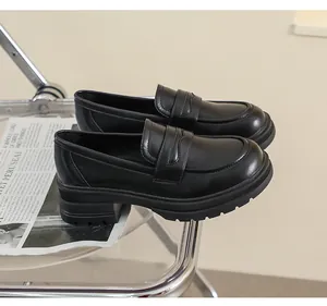 Detalle de mocasines negros con plataforma sobre una silla acrílica para mujeres