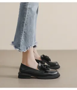 Detalle de mocasines negros con lazo de tela y hebilla metálica dorada Fashion
