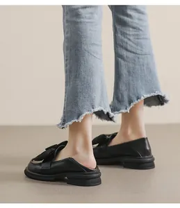 Detalle de mocasines tipo mule de cuero negro con plataforma, lazo y suela antideslizante