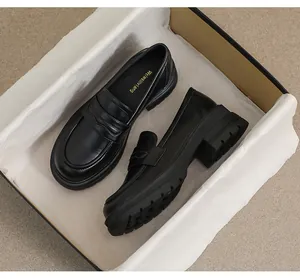 Primer plano de mocasines negros con plataforma en caja con logo dorado en la plantilla
