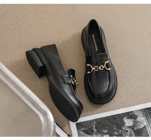Vue de dessus de mocassins noirs mats avec boucle chaîne dorée et semelles épaisses