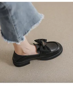 Primer plano de mocasines negros con detalle de lazo y placa de metal dorado arriba