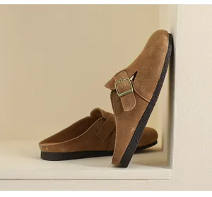 Dettaglio dei sabot in pelle scamosciata color cammello con fibbia in metallo regolabile