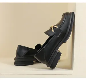 Détail de mocassin noir mat avec boucle dorée et semelle épaisse à plateforme rétro