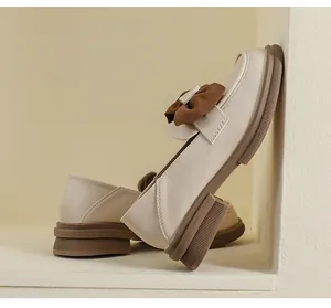 Detalle de mocasín crema con plataforma, lazo marrón y suela de goma antideslizante