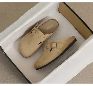 Dettaglio di sabot in camoscio beige con fibbia in metallo vintage e suola in gomma