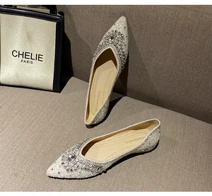 Dettaglio scarpe piatte a punta con fiore di strass scintillanti e finitura avorio