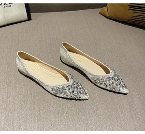 Dettaglio di eleganti ballerine a punta con perle bianche e fibbia in strass scintillanti