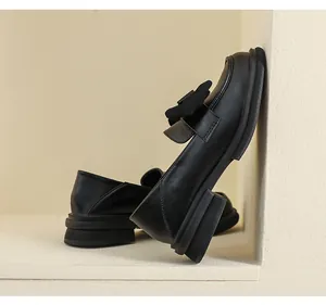 Vista detallada de mocasines negros mates con lazo 3D y suelas de plataforma gruesas