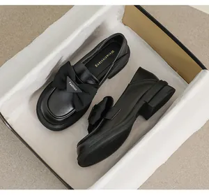 Detalle de mocasines negros para mujer con lazo y hebilla metálica triangular
