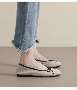 Nahaufnahme der Ballerinas mit quadratischer Spitze, schwarzer Schleife und beigem Leder