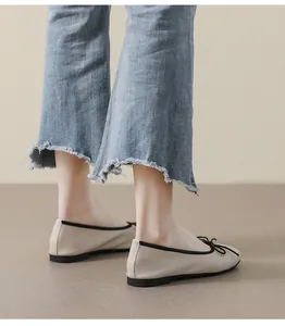Details von beigen Ballerinas aus Leder mit schwarzem Rand und Schleife am Fuß