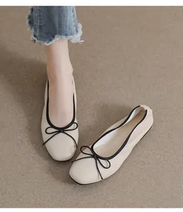 Nahaufnahme beiger Ballerinas mit eckiger Zehenpartie, schwarzem Rand und Schleife