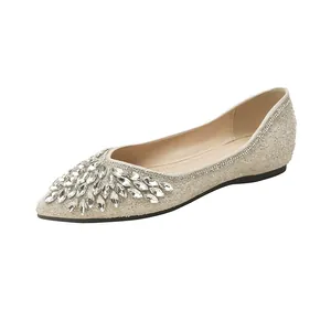Scarpe basse a punta color champagne con strass scintillanti su sfondo bianco