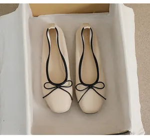 Detail von beigen Ballerinas mit eckiger Zehenpartie, schwarzer Schleife und Lederstruktur