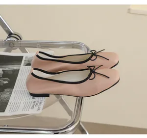 Detail von beige Leder-Ballerinas mit eckiger Spitze und schwarzer Schleife auf Glas