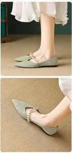 Detail view of light green pointed flat shoes featuring textured fabric and pearl strap