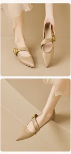 Detail of pointed-toe Mary Jane flat with cross strap and large gold metal buckle