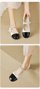 Close-up of black-and-white Mary Jane flats with silver chain and pearl detail