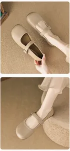 Detailed macro view of beige round-toe Mary Jane shoes with fine metal buckle strap