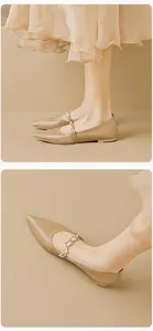 Detail von spitzen Mary Jane Ballerinas mit dekorativer Metallkette und Perlenriemen