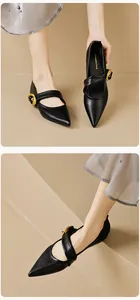 Macro view of black pointed toe Mary Jane flats with elegant large gold buckles