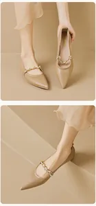 Nahaufnahme von spitzen flachen Schuhen mit eleganter Metallkette und Perlenverzierung