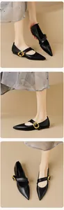 Close-up of black pointed-toe Mary Jane flats with large gold buckles and smooth leather