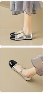 Detail of silver Mary Jane flat with black toe cap, metal chain, and pearl accent