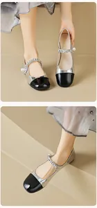 Detail of silver Mary Jane flats featuring a black cap toe and pearl chain strap